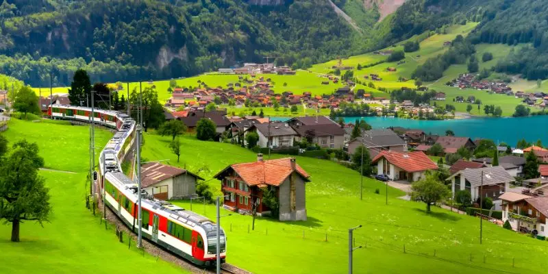 Mountain landscape in switzerland with a train passing through valleys and lakes.