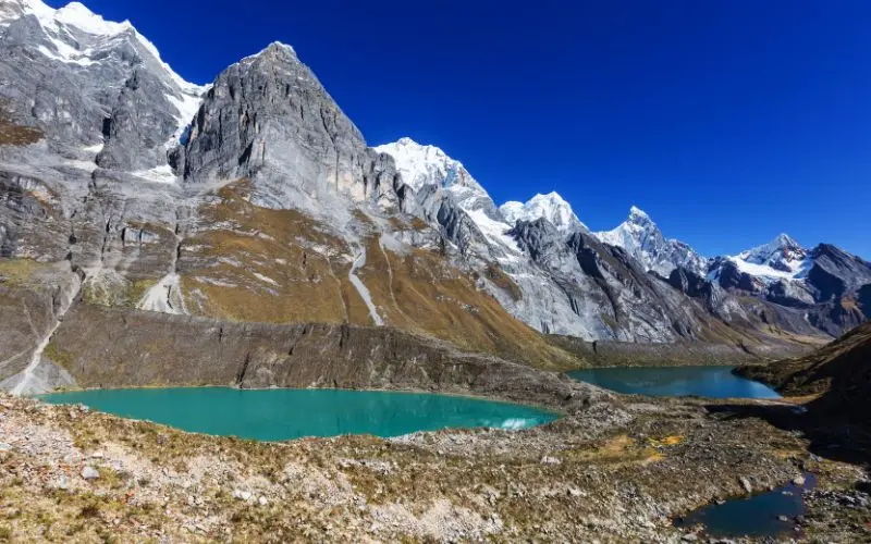 Snow-covered cordillera blanca mountains around turquoise lake near huaraz peru