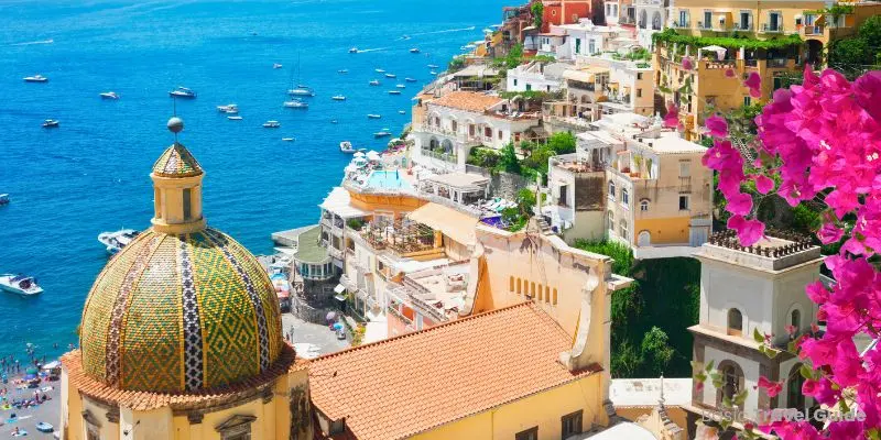 Italian riviera shoreline with colorful houses, cliffs, and calm ocean waters.